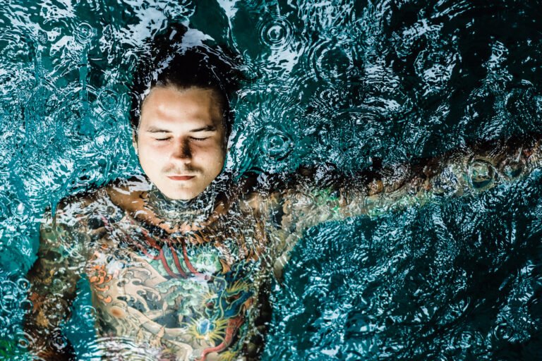 tattooed man in the pool in the rain